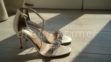 漂亮的水晶鞋在阳光下闪闪发光。 行动。 新娘`结婚的双鞋站在阳光下。 优雅的新娘